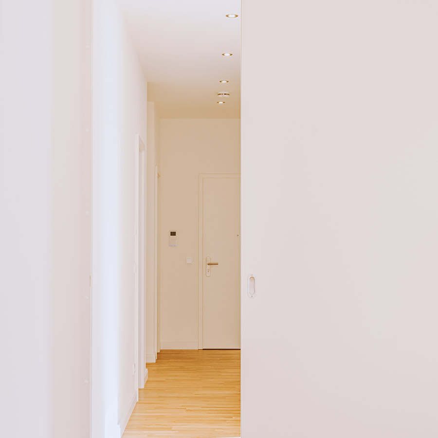 Heller Flur mit Parkettboden und weißen Wänden in moderner Neubauwohnung – Blick zur Eingangstür