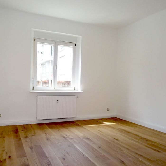 Helles Zimmer mit Fenster, weiß gestrichenen Wänden und hochwertigem Parkettboden in renovierter Altbauwohnung