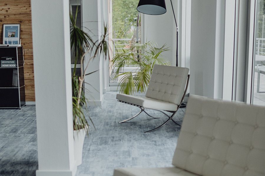 Moderner Wartebereich mit Designerstühlen, Pflanzen und großen Fenstern – stilvolle Büro- oder Praxisräume